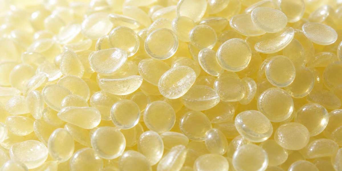 Close-up of translucent, light yellow C5 petroleum hydrocarbon resin pellets for industrial manufacturing.